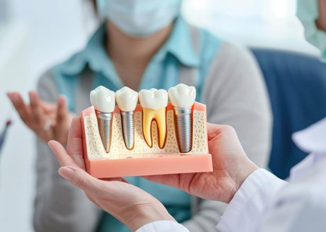 Dentist holding dental implant model, speaking to patient