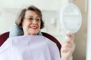 a dental patient admiring their smile in a handheld mirror